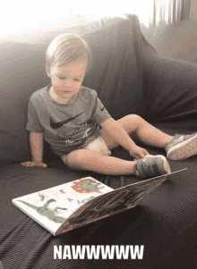 a little boy is sitting on a couch reading a book with the words nawwwwww on the bottom