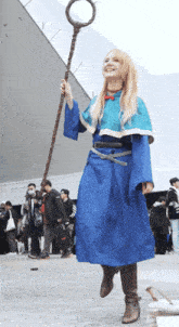 a woman in a blue dress is holding a cane and smiling