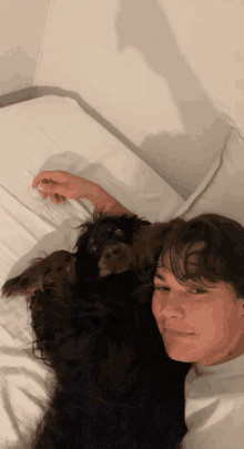 a young man is laying on a bed with a dog