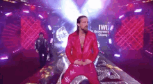 a man in a red jacket and red pants is standing on a stage in front of a sign that says heavyweight champion .