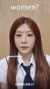 a woman with long red hair is wearing a tie and a white shirt and is looking at the camera .