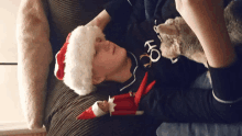 a boy wearing a santa hat is laying on a couch with a teddy bear