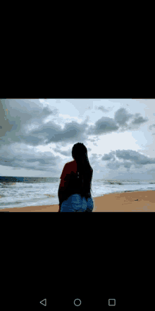 a woman standing on a beach looking at the ocean .