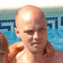 a bald man is standing next to a woman in front of a pool .