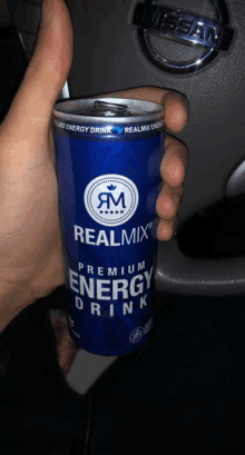 a person holds a can of realmix premium energy drink