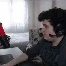 a man wearing headphones and a microphone is sitting at a desk .