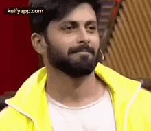 a man with a beard wearing a yellow jacket is making a funny face .