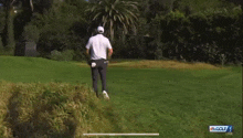 a man in a white shirt and black pants is running on a golf course in front of a sign that says golf live