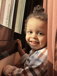 a child sitting in front of a window with uv resistance written on the glass