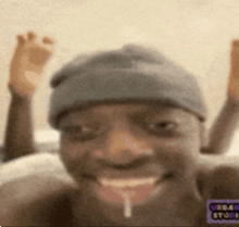 a man wearing a beanie is making a funny face with his mouth open and his hands up .