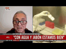 a man wearing glasses is talking on a news channel next to a picture of a robot .