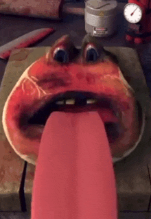 a cartoon character with a long tongue sticking out from its mouth is sitting on a cutting board .