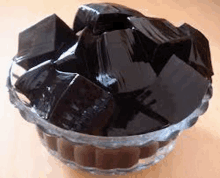 a bowl filled with black jelly cubes on a table .