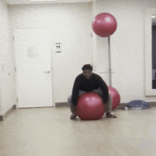 a man sits on a pink exercise ball in front of a sign that says ' t & t '