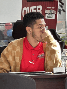 a man sitting at a desk in front of a sign that says " over "