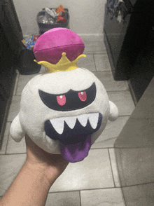 a person is holding a stuffed king boo with a crown on top