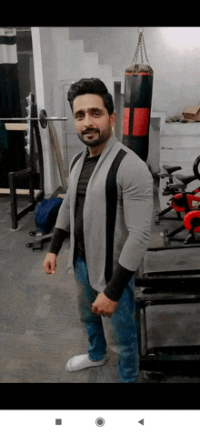 a man with a beard is standing in a gym next to a punching bag .