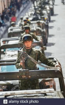 a soldier is standing in the back of a military vehicle .