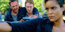 a group of people are standing next to each other and one of them is holding a gun in his hand .
