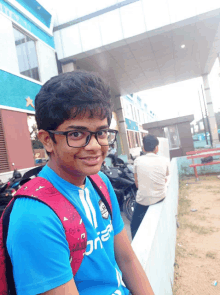 a young boy wearing glasses and a blue shirt that says ' one2 ' on it