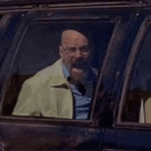 a man with a beard is sitting in a car looking out of the window .