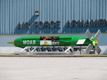 a green moab bomb sits in front of the air force armamen