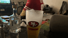 a bottle of vodka sits next to a 49ers beer glass