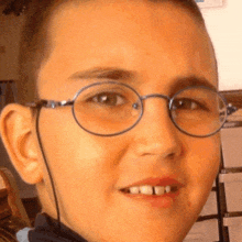 a young boy wearing glasses looks at the camera and smiles