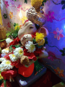 a statue of ganesha is surrounded by flowers and a crown