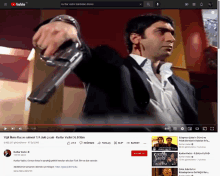 a man in a suit is holding a gun on a youtube screen