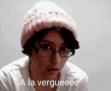 a woman wearing a pink beanie and glasses is making a funny face .
