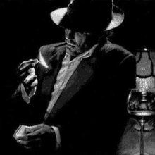 a man in a suit is smoking a cigarette and holding a glass of wine .