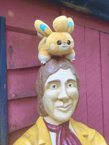 a statue of a man has a stuffed animal on top of his head