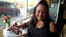 a woman sits at a table with a plate of cake