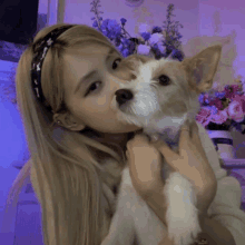 a woman is kissing a small brown and white dog on the nose