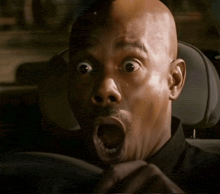 a man with a surprised look on his face is sitting in a car