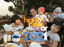 a woman holding a baby sits at a table with a sign that says " happy new year 2021 "