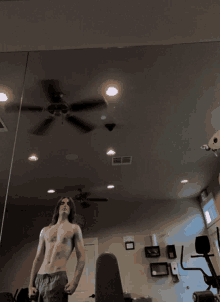 a shirtless man in a gym with a ceiling fan