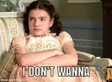 a girl in a pink dress is sitting on a couch with her arms crossed and says i don t wanna