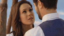 a man and a woman are looking at each other with a blue sky in the background