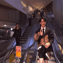 a man in a suit and tie is standing on an escalator in front of a sign that says ' icon '