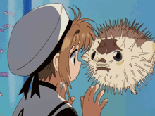 a girl in a sailor hat is touching a puffer fish with her hand