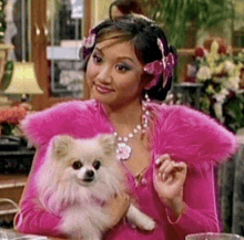 a woman in a pink dress is holding a small dog .