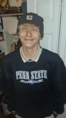 a man wearing a penn state sweatshirt and a carhartt beanie