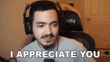 a man wearing headphones and a microphone is sitting in front of a computer and saying `` i appreciate you '' .