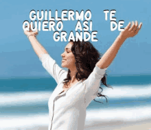 a woman is standing on a beach with her arms outstretched and the words " quiero asi grande " are above her