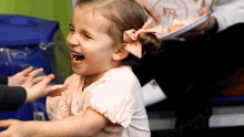 a little girl with a pink bow in her hair is laughing while a man holds a plate of food with nfl on it