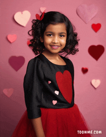 a little girl is wearing a black top with a red heart on it and a red skirt