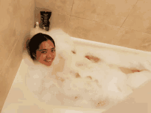 a woman is taking a bath in a bathtub with a bottle of shampoo on the wall