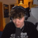 a young man wearing headphones is sitting in front of a microphone in a room .